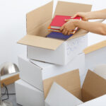 Person filling moving boxes with books.